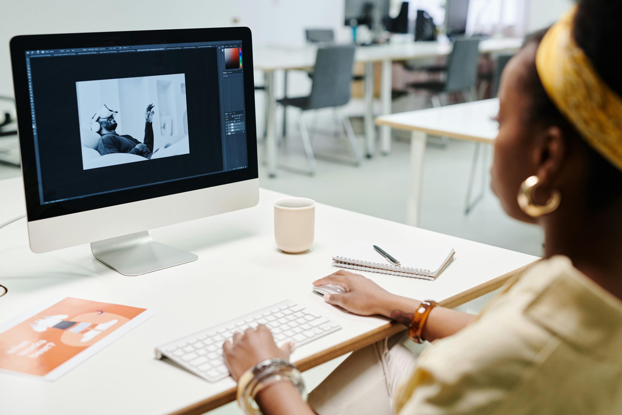 A woman using a computer for image editing in a bright, modern office setting.